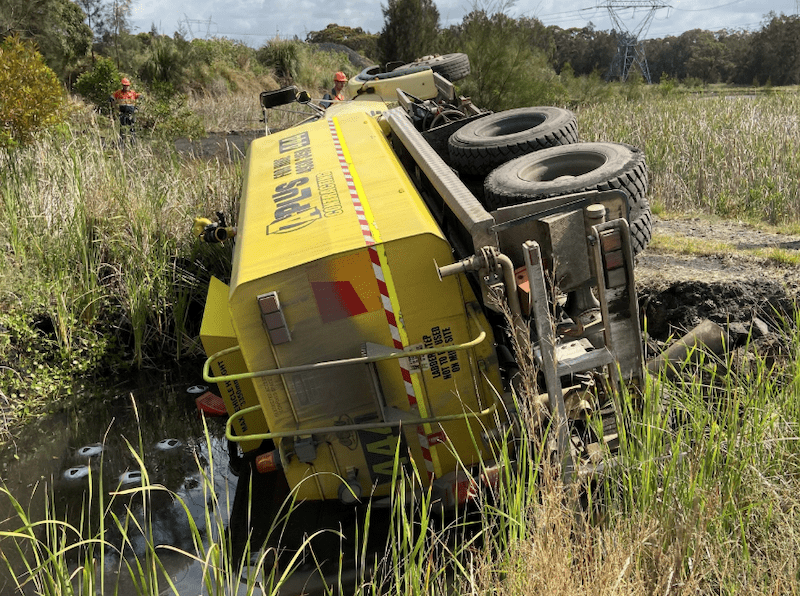 dangers of operating near water. truck on its side water storage dam